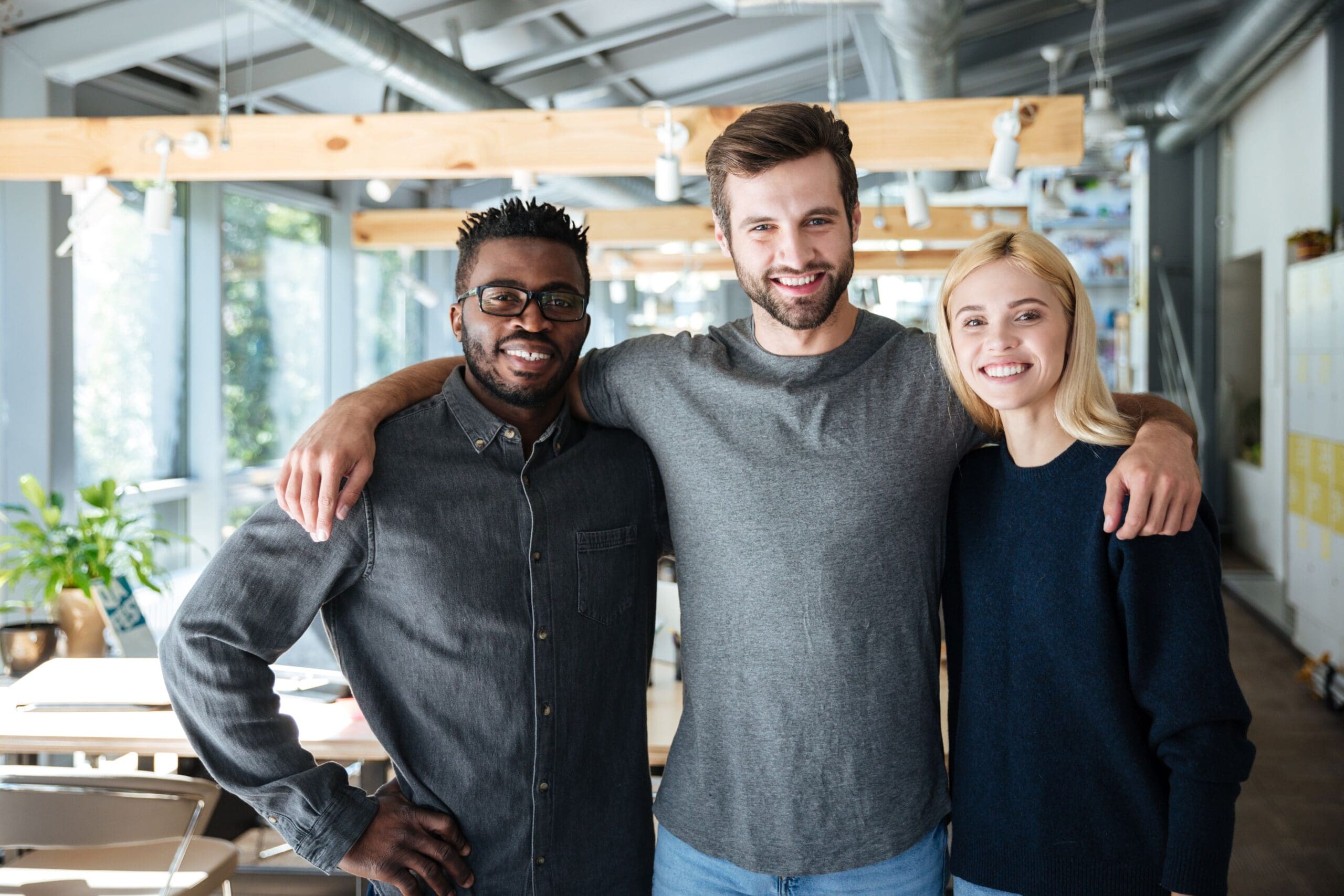Smiling young colleagues standing together in a modern office, promoting collaboration and teamwork for Flexigrow's referral program.